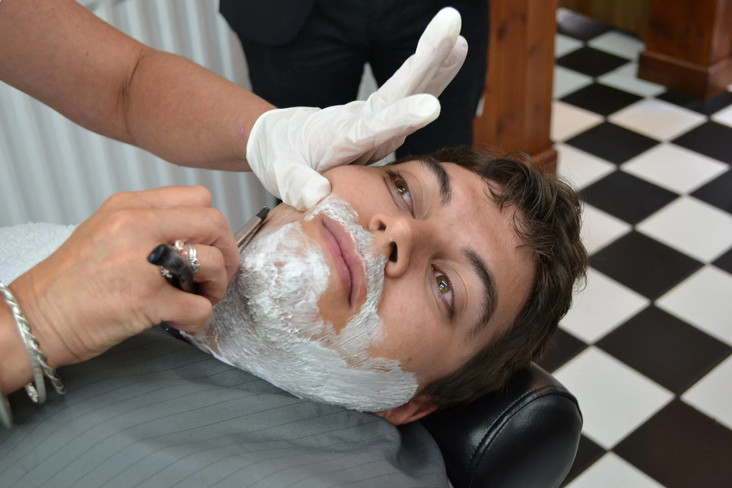A client receiving a hot towel shave in the shop