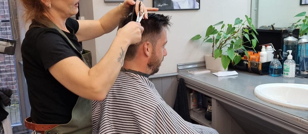 A barber giving a client a haircut inside the Legends Barber Shop in Taunton